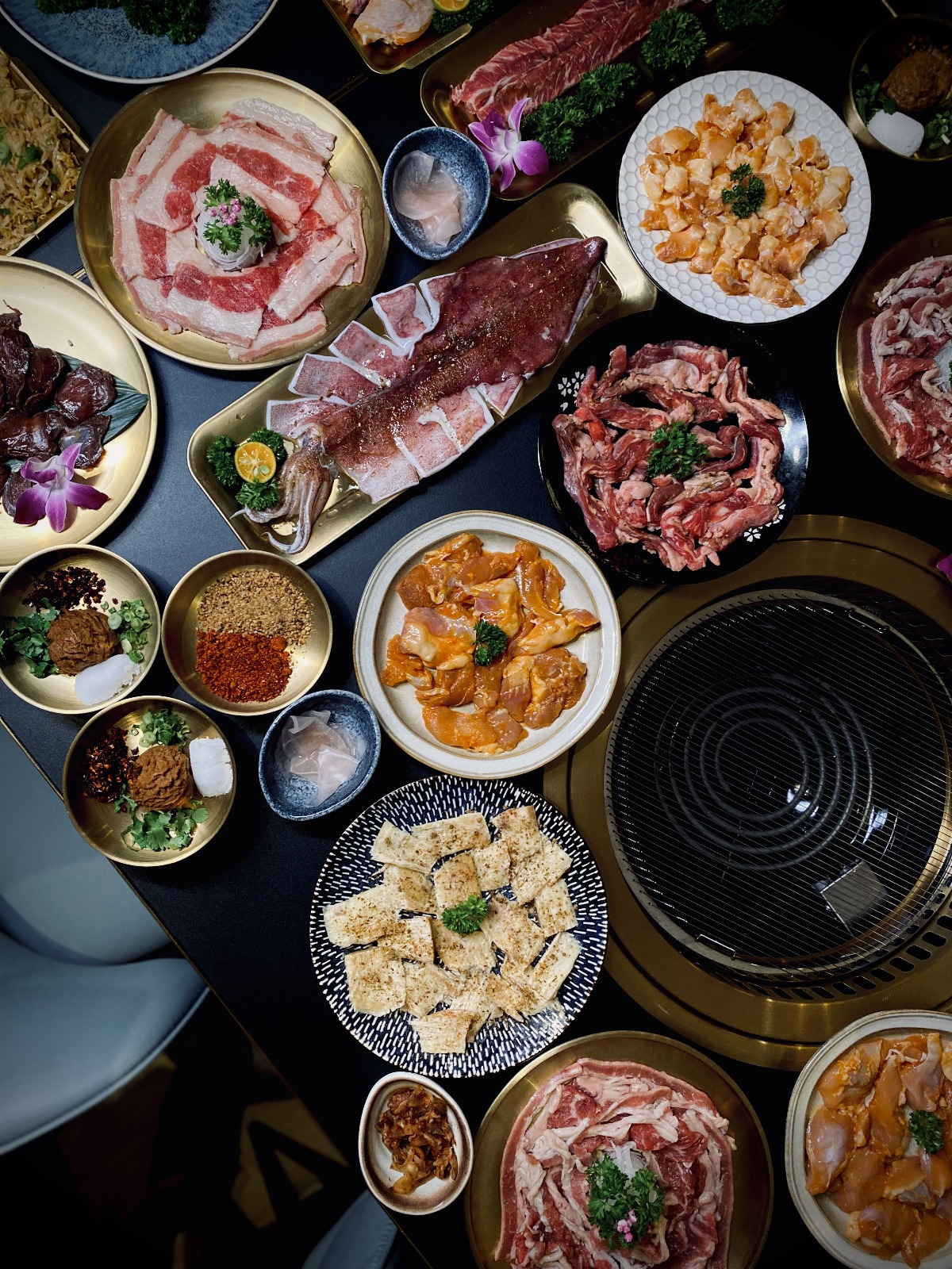 Overhead spread of grilled meats, seafood and condiments